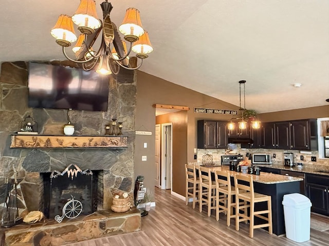 149 Poormans Trl, Murphy, NC 28906 - kitchen featuring stainless steel microwave, a chandelier, wood finished floors, vaulted ceiling, and under cabinet range hood