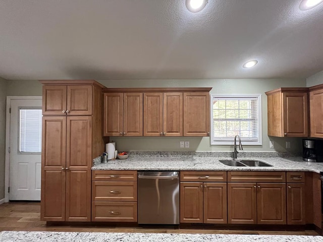 kitchen with dishwasher, light stone countertops, sink, and light hardwood / wood-style flooring