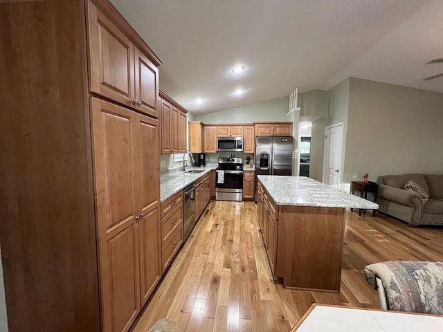 kitchen featuring stainless steel appliances, a kitchen island, sink, light hardwood / wood-style floors, and lofted ceiling