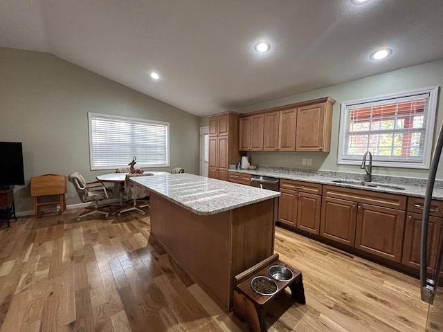 kitchen with light stone counters, a center island, vaulted ceiling, sink, and light hardwood / wood-style flooring