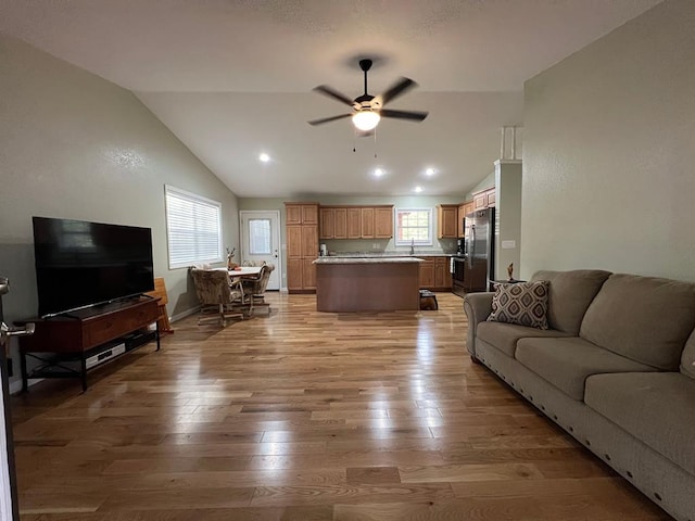 living room with light wood-type flooring, lofted ceiling, and ceiling fan