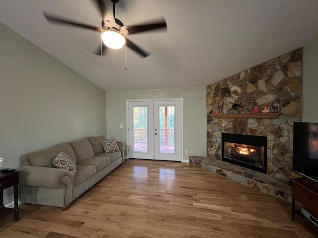 living room with a stone fireplace, french doors, light hardwood / wood-style flooring, and lofted ceiling