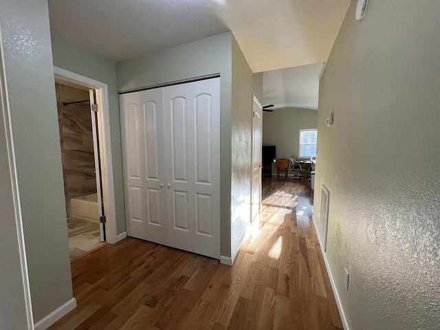 hall with hardwood / wood-style floors and vaulted ceiling