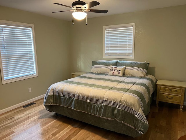 bedroom with ceiling fan, wood-type flooring, and multiple windows