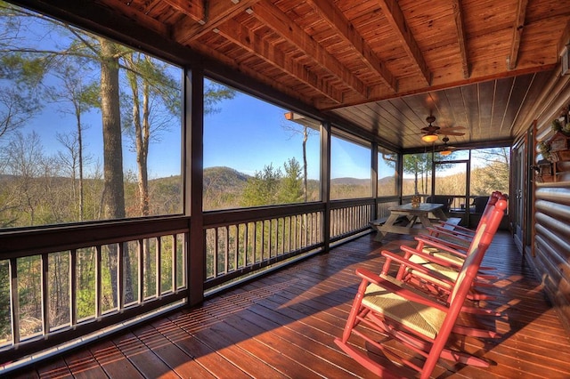 unfurnished sunroom with ceiling fan, wood ceiling, and beamed ceiling