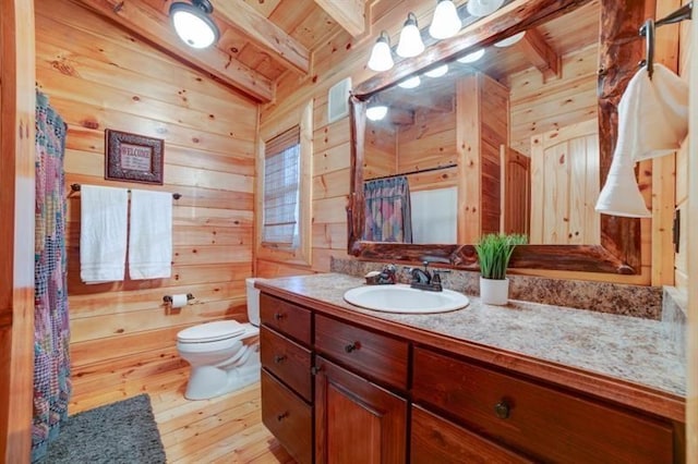 full bath featuring wood walls, beam ceiling, vanity, toilet, and hardwood / wood-style floors