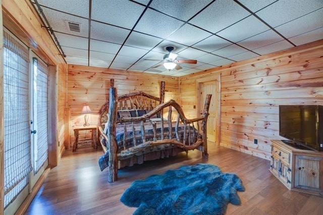 bedroom with visible vents, wood walls, a paneled ceiling, and wood finished floors
