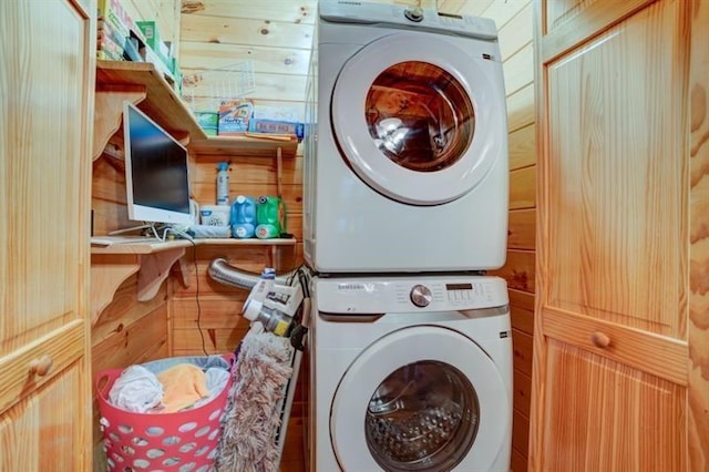 washroom with laundry area, wood walls, and stacked washer and clothes dryer