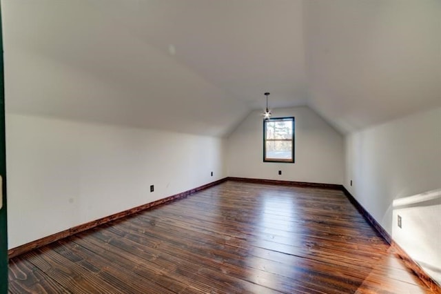 additional living space with baseboards, vaulted ceiling, and dark wood-type flooring