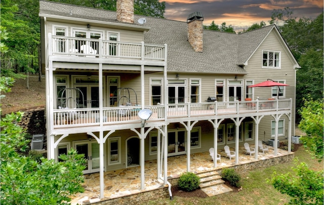 back house at dusk featuring a patio area and central air condition unit