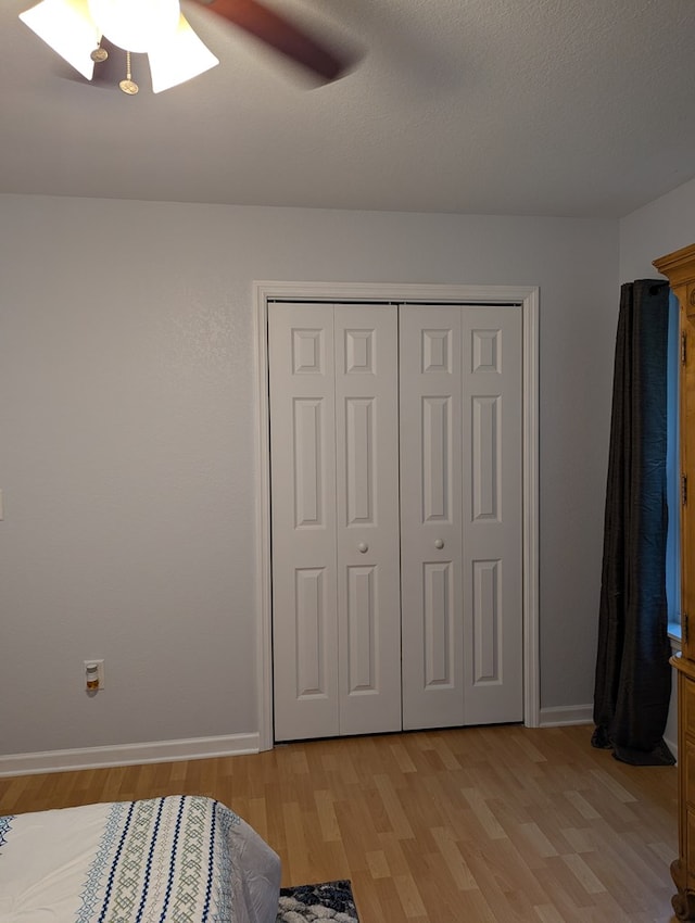 bedroom featuring a textured ceiling, light hardwood / wood-style flooring, a closet, and ceiling fan