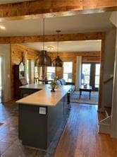 kitchen featuring hanging light fixtures, beamed ceiling, a kitchen island, and dark hardwood / wood-style flooring