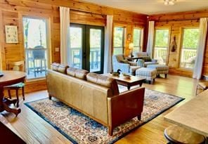 living room with light wood-type flooring, french doors, and wood walls