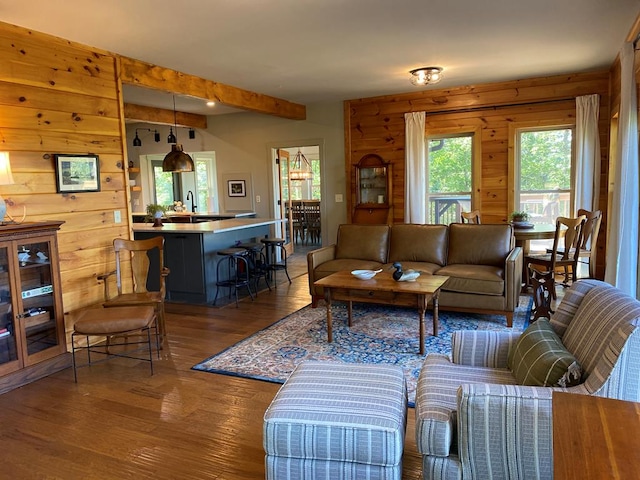 living room featuring beamed ceiling, dark hardwood / wood-style floors, and wooden walls