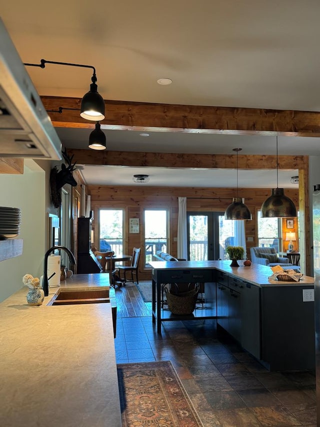 kitchen with hanging light fixtures, a healthy amount of sunlight, sink, and beam ceiling