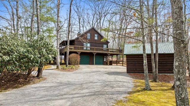 rustic home with a garage, metal roof, a wooden deck, and driveway