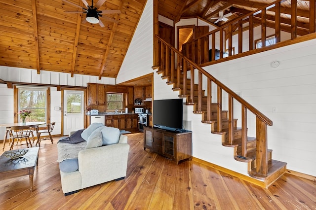 living room featuring light wood finished floors, stairway, beamed ceiling, wood walls, and wood ceiling