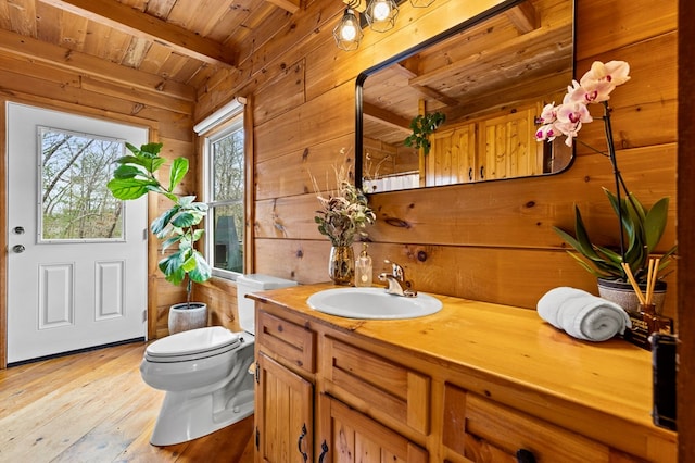 bathroom with beamed ceiling, wood walls, wood ceiling, toilet, and hardwood / wood-style floors