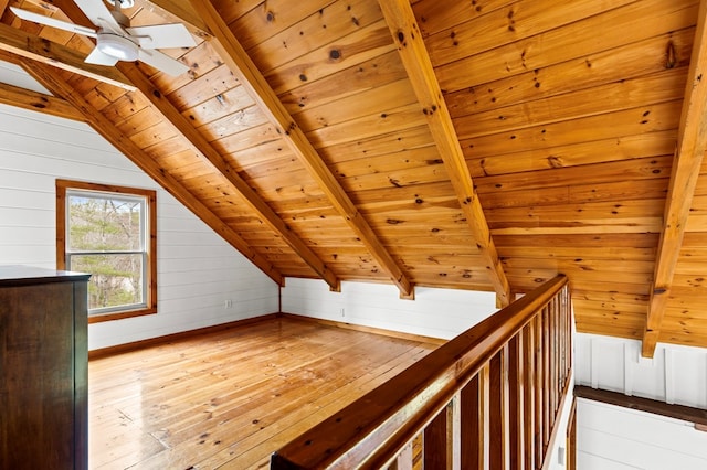 interior space with wooden walls, wooden ceiling, vaulted ceiling with beams, and light wood-type flooring