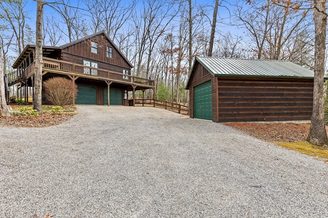 view of side of home with an outbuilding, a deck, driveway, metal roof, and a garage