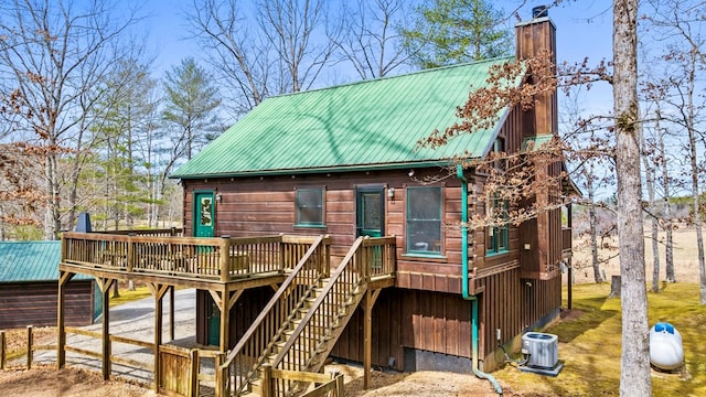 exterior space featuring a deck, stairway, metal roof, central AC unit, and a chimney