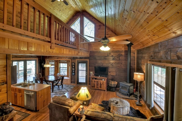 living room featuring a healthy amount of sunlight, a wood stove, wood-type flooring, and wood walls