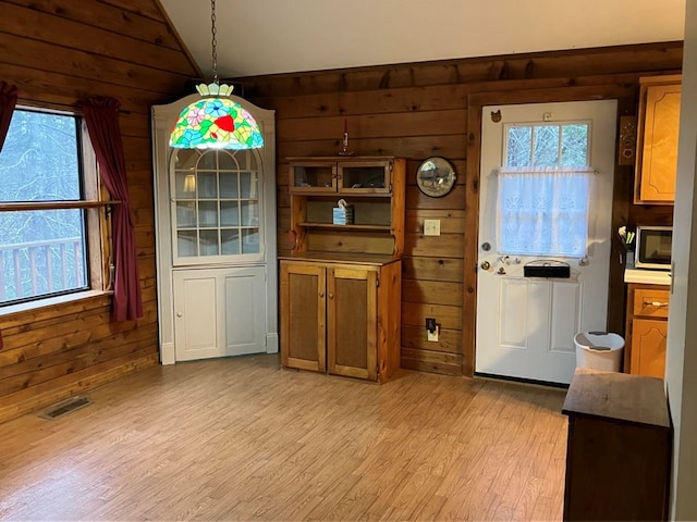 147 Holly Ridge Ln, Murphy, NC 28906 - unfurnished dining area featuring lofted ceiling, wooden walls, and light hardwood / wood-style flooring