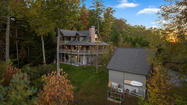 rear view of property with a balcony, a patio area, and a yard