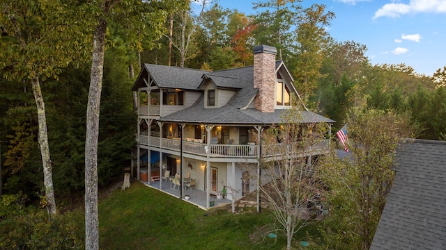 rear view of house with a balcony, a yard, and a patio area