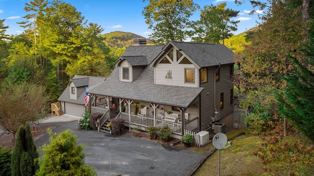 view of front facade featuring a mountain view, a garage, a porch, and central AC