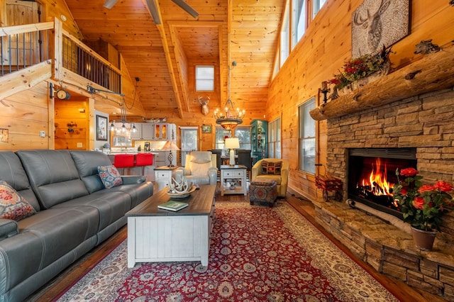 living room with beam ceiling, a stone fireplace, wood ceiling, high vaulted ceiling, and an inviting chandelier