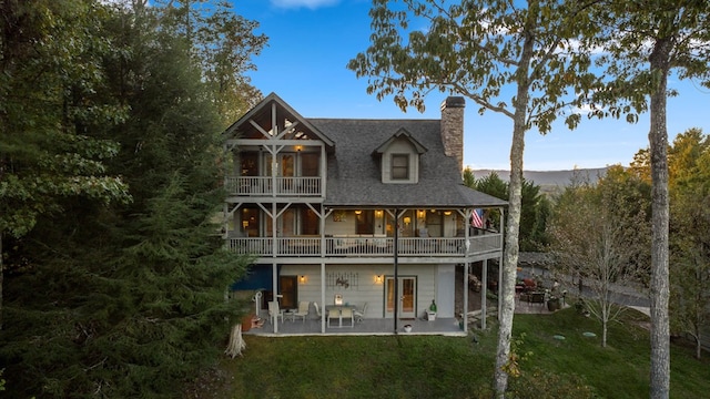 back of house with a patio area, a lawn, and a balcony