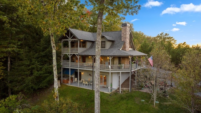 back of house featuring a balcony, a patio, and a yard