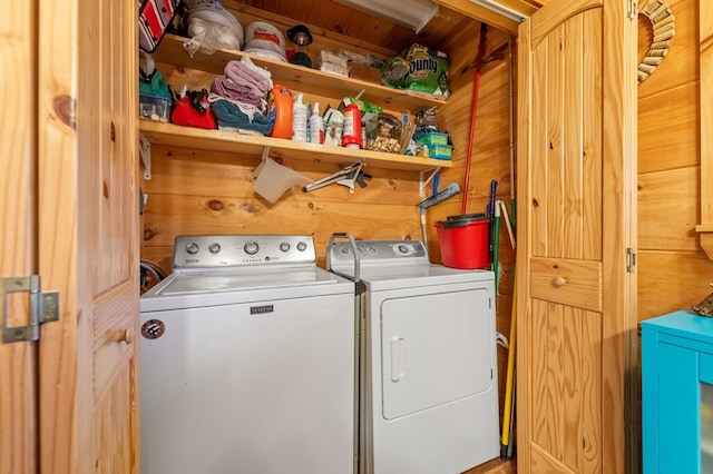 laundry room with wood walls and washing machine and clothes dryer