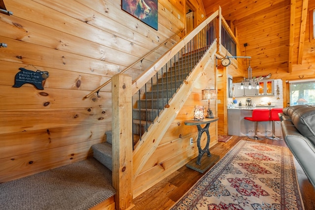 staircase featuring wood walls, a high ceiling, and hardwood / wood-style floors