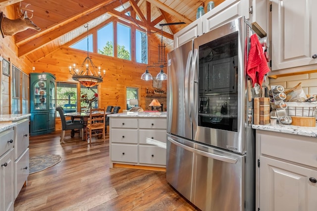 kitchen with decorative light fixtures, white cabinets, beam ceiling, and stainless steel fridge