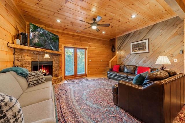 living room featuring french doors, a stone fireplace, wood ceiling, and wooden walls