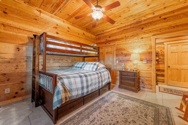 bedroom featuring ceiling fan, wooden ceiling, light tile patterned floors, and wood walls