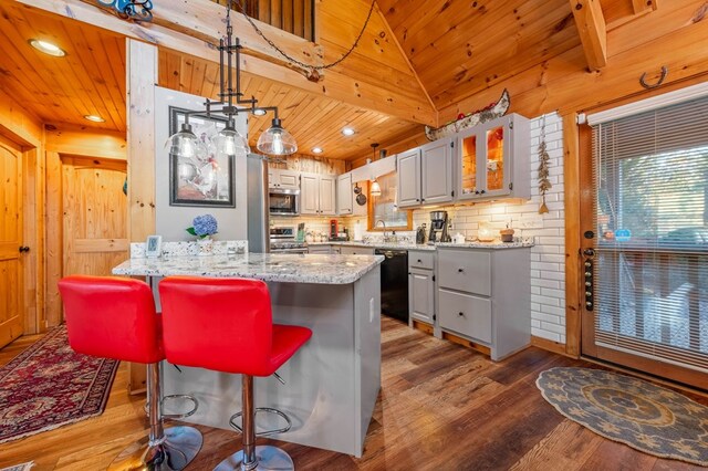 kitchen featuring light stone countertops, wood ceiling, decorative light fixtures, stainless steel appliances, and a breakfast bar area