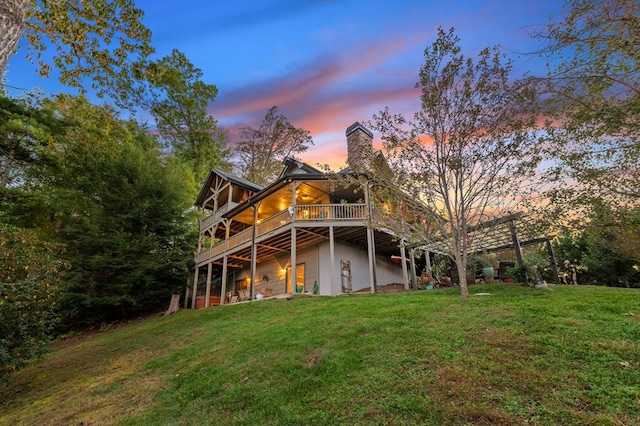 back house at dusk with a yard and a deck