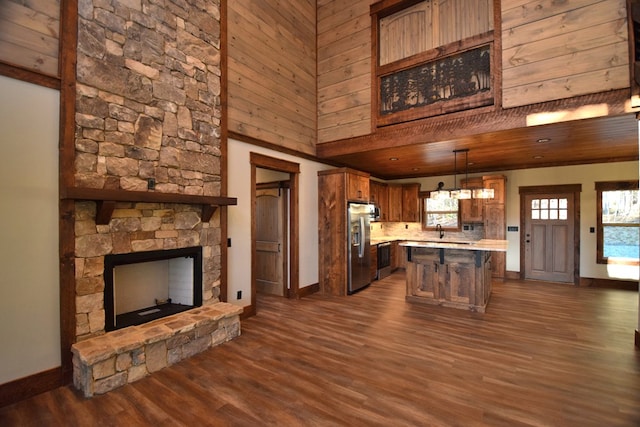 kitchen with pendant lighting, dark hardwood / wood-style floors, a towering ceiling, a kitchen island, and stainless steel fridge with ice dispenser