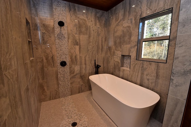 bathroom with a tub to relax in and tile walls