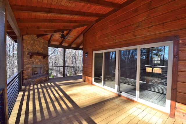 unfurnished sunroom with wooden ceiling, ceiling fan, lofted ceiling with beams, and an outdoor stone fireplace