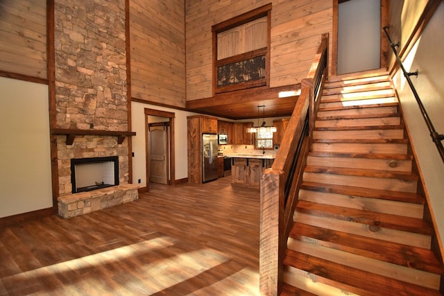 staircase featuring a fireplace, hardwood / wood-style floors, a towering ceiling, and a chandelier