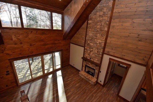 unfurnished living room with a fireplace, a towering ceiling, dark hardwood / wood-style floors, and a healthy amount of sunlight