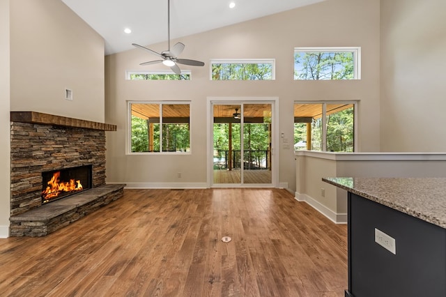 unfurnished living room featuring a fireplace, light wood-type flooring, high vaulted ceiling, and ceiling fan