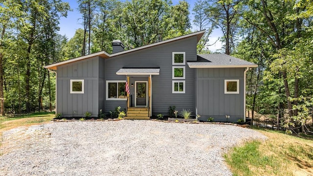 view of front facade featuring a shingled roof, board and batten siding, and a chimney