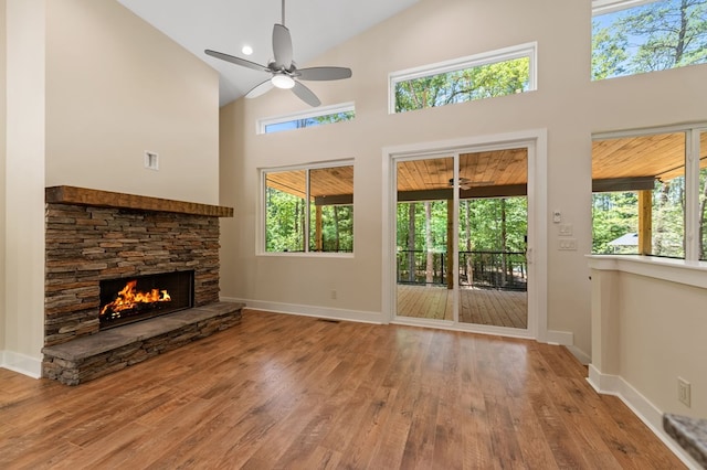 unfurnished living room with ceiling fan, a fireplace, high vaulted ceiling, and wood-type flooring