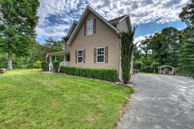 view of side of property featuring a yard, covered porch, and a storage unit