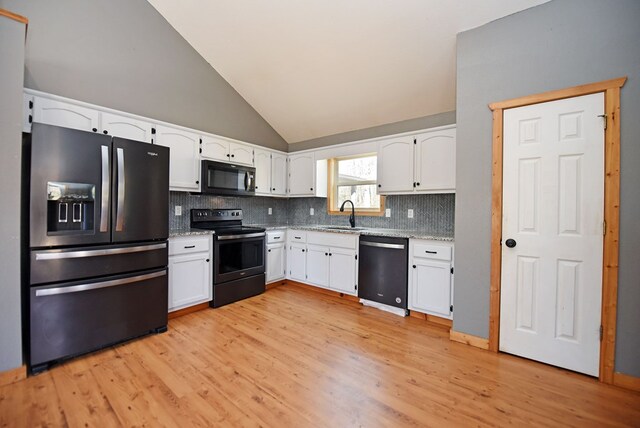 kitchen featuring lofted ceiling, sink, tasteful backsplash, black appliances, and white cabinets